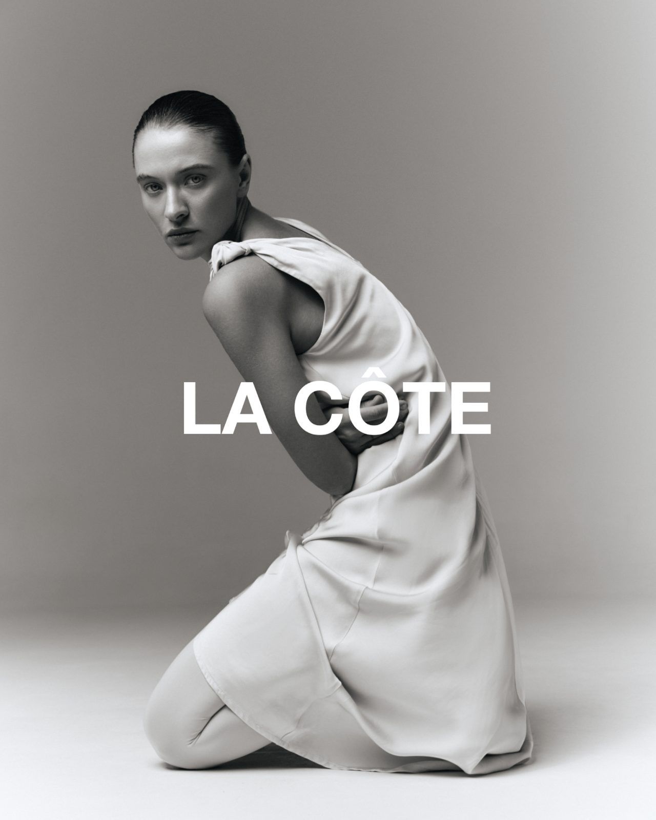 LA CÔTE — campaign, kneeling figure in a pale satin one-shoulder dress, black-and-white