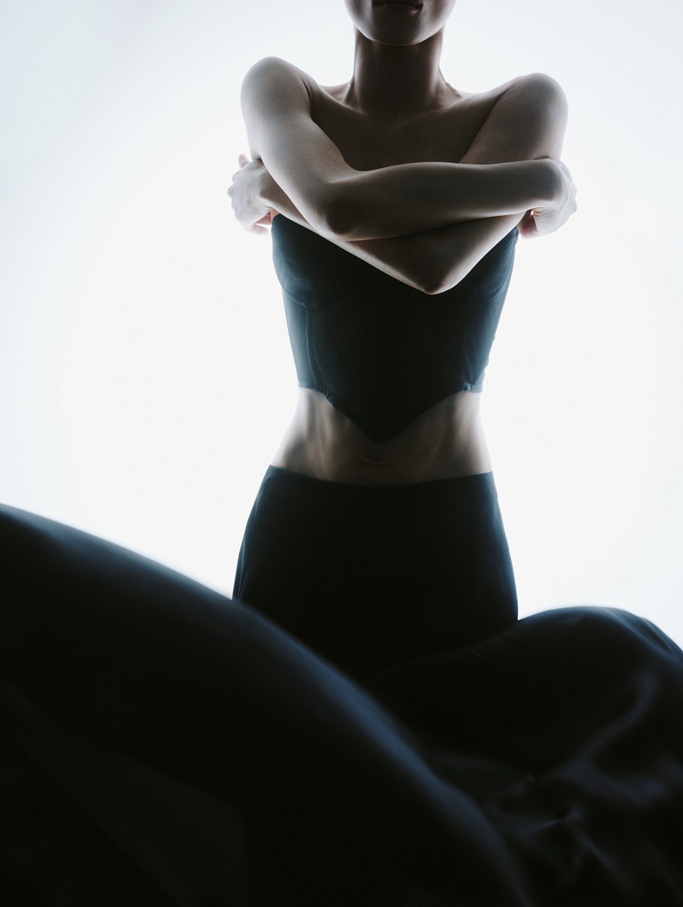 MIOGI LI — corset silhouette with crossed arms against the light