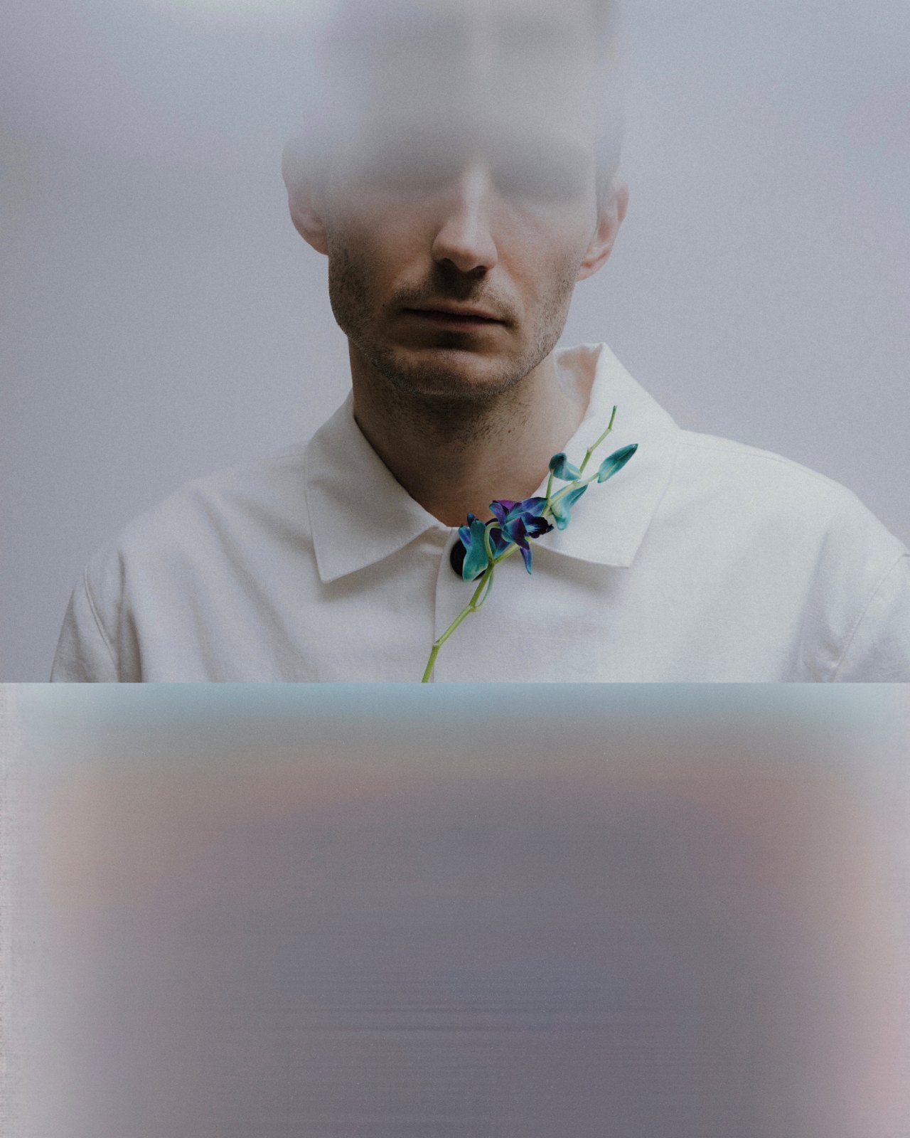 Editorial — portrait behind frosted glass with a blue orchid at the collar