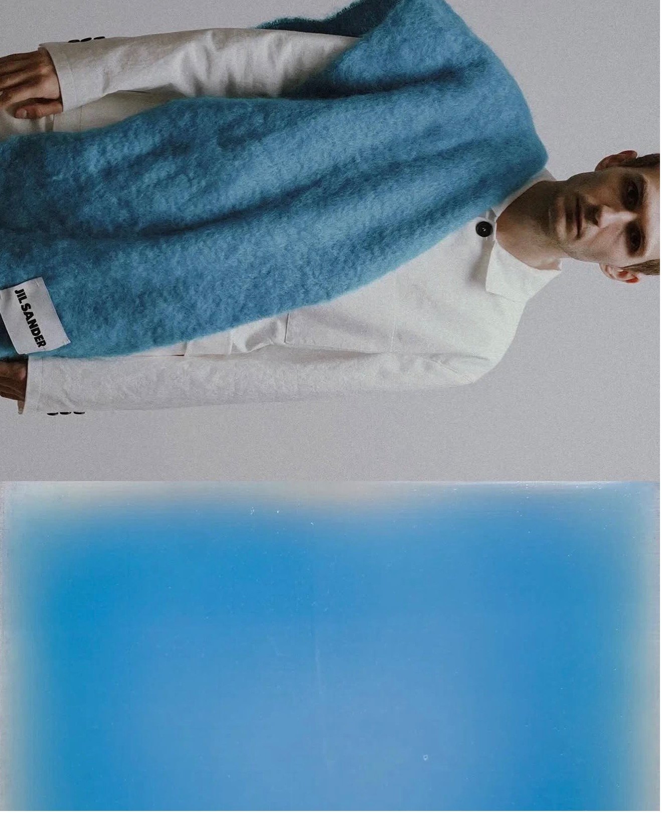 Portrait in a white Jil Sander shirt with a blue mohair scarf, above a blue work