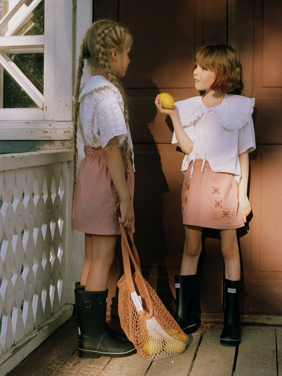 POLUSHA — campaign, two girls with a lemon on a wooden porch