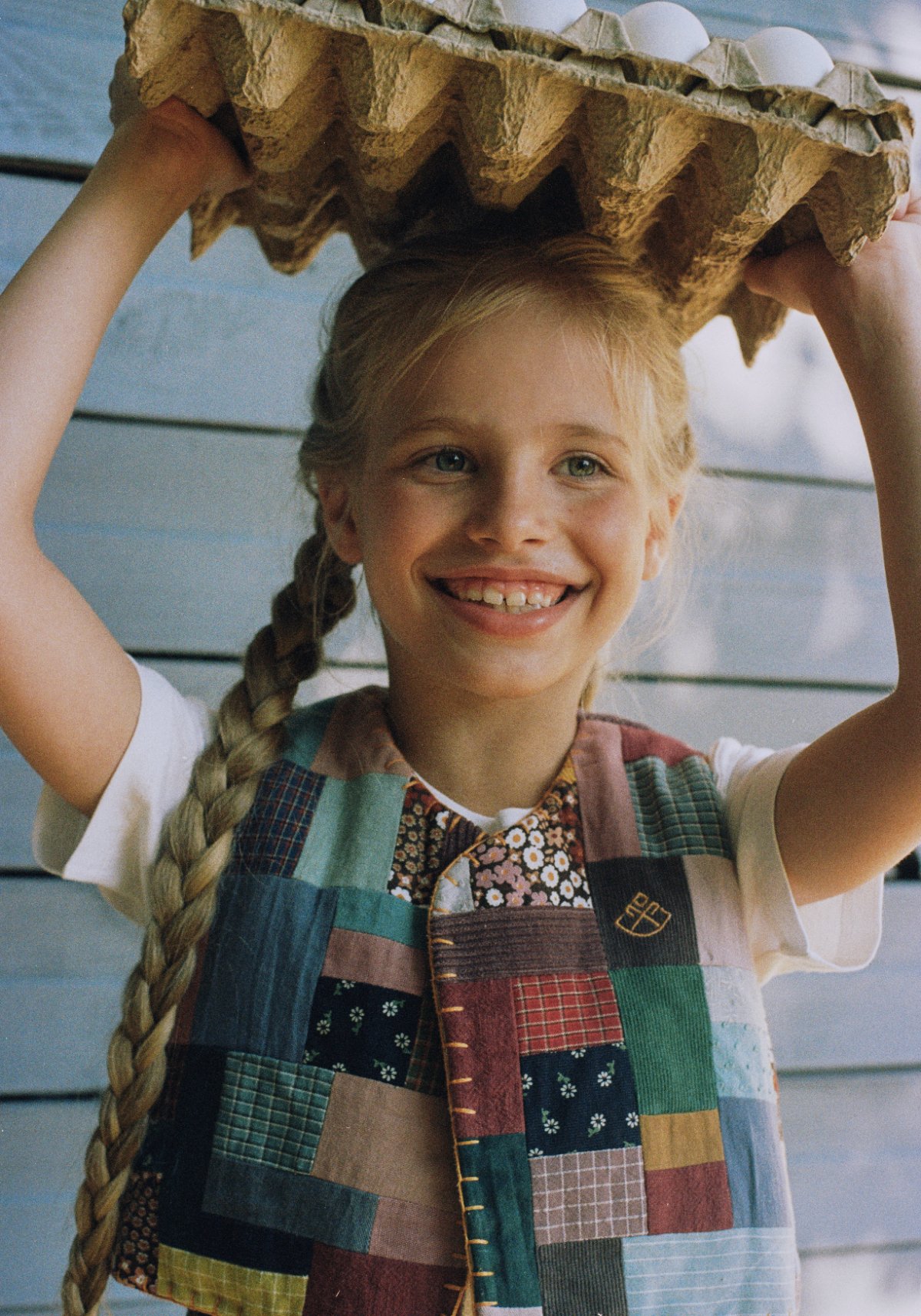 POLUSHA — campaign, girl in a patchwork vest holding a tray of eggs