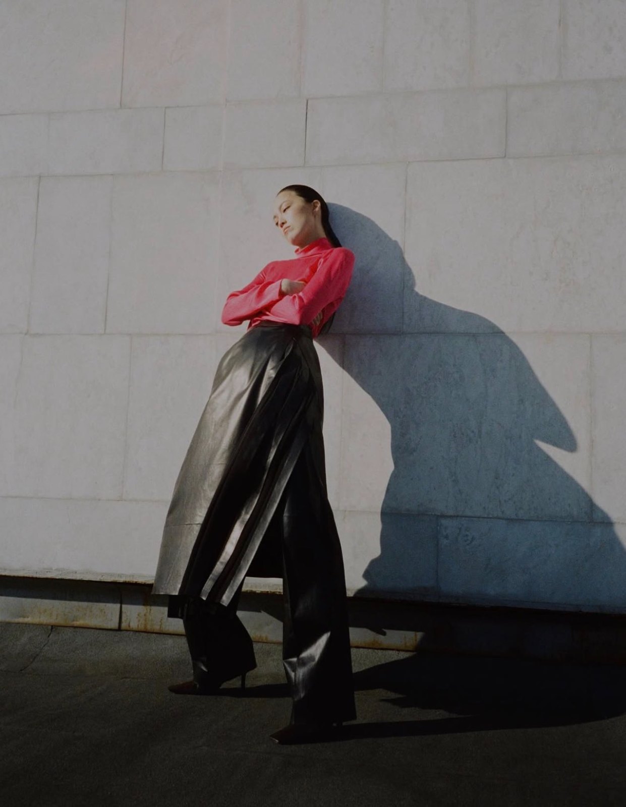 Editorial — crimson knit and black leather against a sunlit stone wall