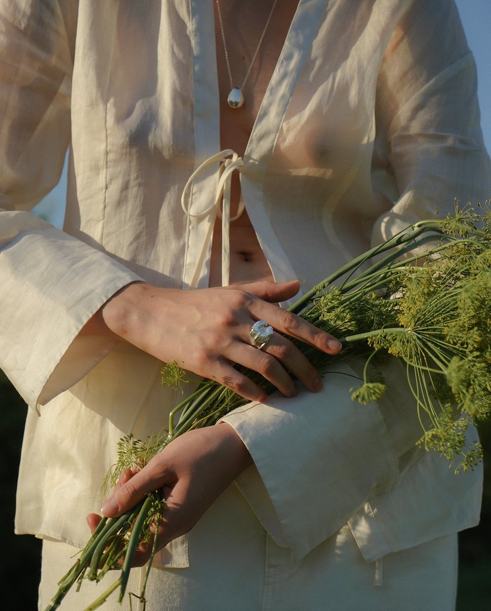 SHU SHA — hands with a silver ring holding dill umbels in evening light
