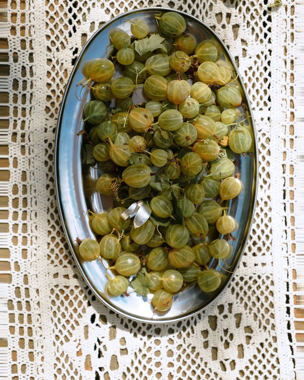 SHU SHA — gooseberries with silver earrings on a steel tray over lace