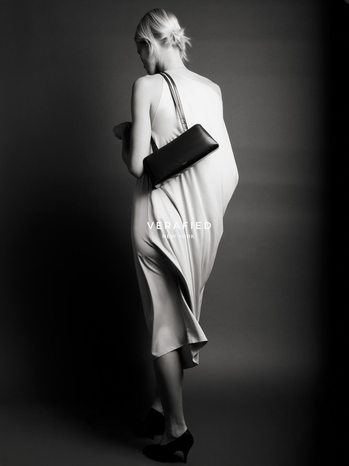 VERAFIED New York — portrait in a pale blue one-shoulder dress with a brown clutch